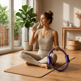 Femme assise avec l'anneau de Pilates Lyvae mauve, pause hydratation à la maison