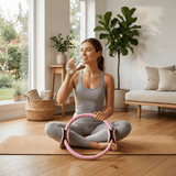 Femme assise avec l'anneau de Pilates Lyvae rose, pause hydratation à la maison